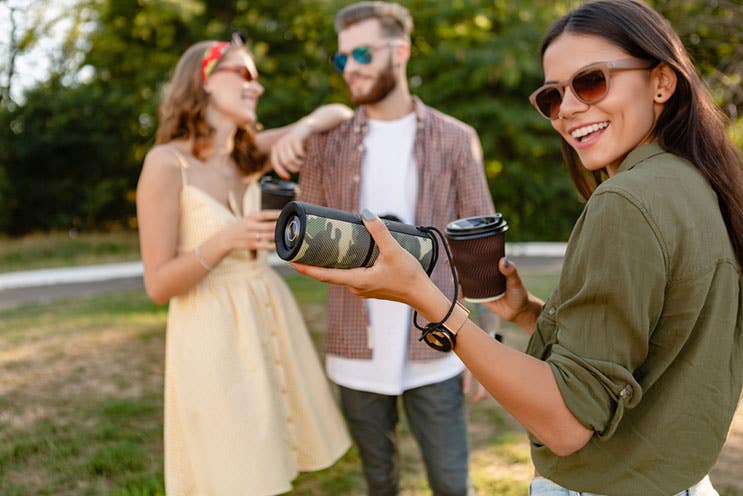 smiling woman holding portable speaker